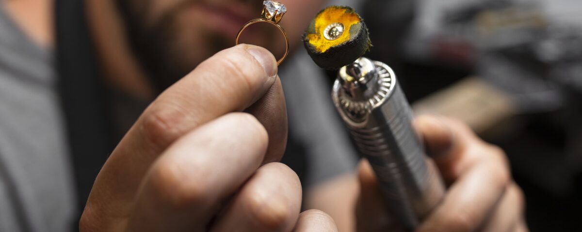 Close-up of a jeweler carefully working on a gold ring using a precision polishing tool. Expert craftsmanship in jewelry making.