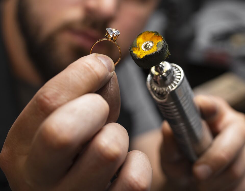 Close-up of a jeweler carefully working on a gold ring using a precision polishing tool. Expert craftsmanship in jewelry making.